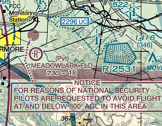 Sectional chart excerpt east of Livermore, California. A small solid magenta shape sits in the upper left of the frame, with a magenta dotted leader line running from it down to a magenta-outlined box. The box reads, in magenta capitals: NOTICE, FOR REASONS OF NATIONAL SECURITY PILOTS ARE REQUESTED TO AVOID FLIGHT AT AND BELOW 800 feet AGL IN THIS AREA. At the right a small blue polygon whose inward hatch ticks fill its whole interior carries the designation R-2531.