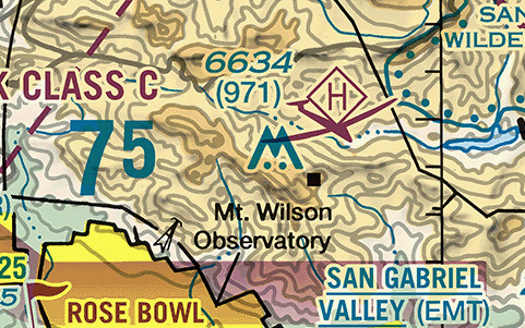 A sectional chart excerpt of a mountain ridge in tan and pale green with fine brown contour lines. Near the center stands a blue symbol shaped like two joined peaks with three dots at its base and two dots above it. Printed above the symbol in blue is 6634, and directly below that, in parentheses, 971. A small black square to the right is labelled Mt. Wilson Observatory in black type. A magenta hexagon containing the letter H sits above and right of the obstruction symbol. At the left edge the words CLASS C print in blue beside a large blue 75, and at the bottom of the frame a black landmark square is labelled ROSE BOWL and an airport name reads SAN GABRIEL VALLEY, with EMT in parentheses.