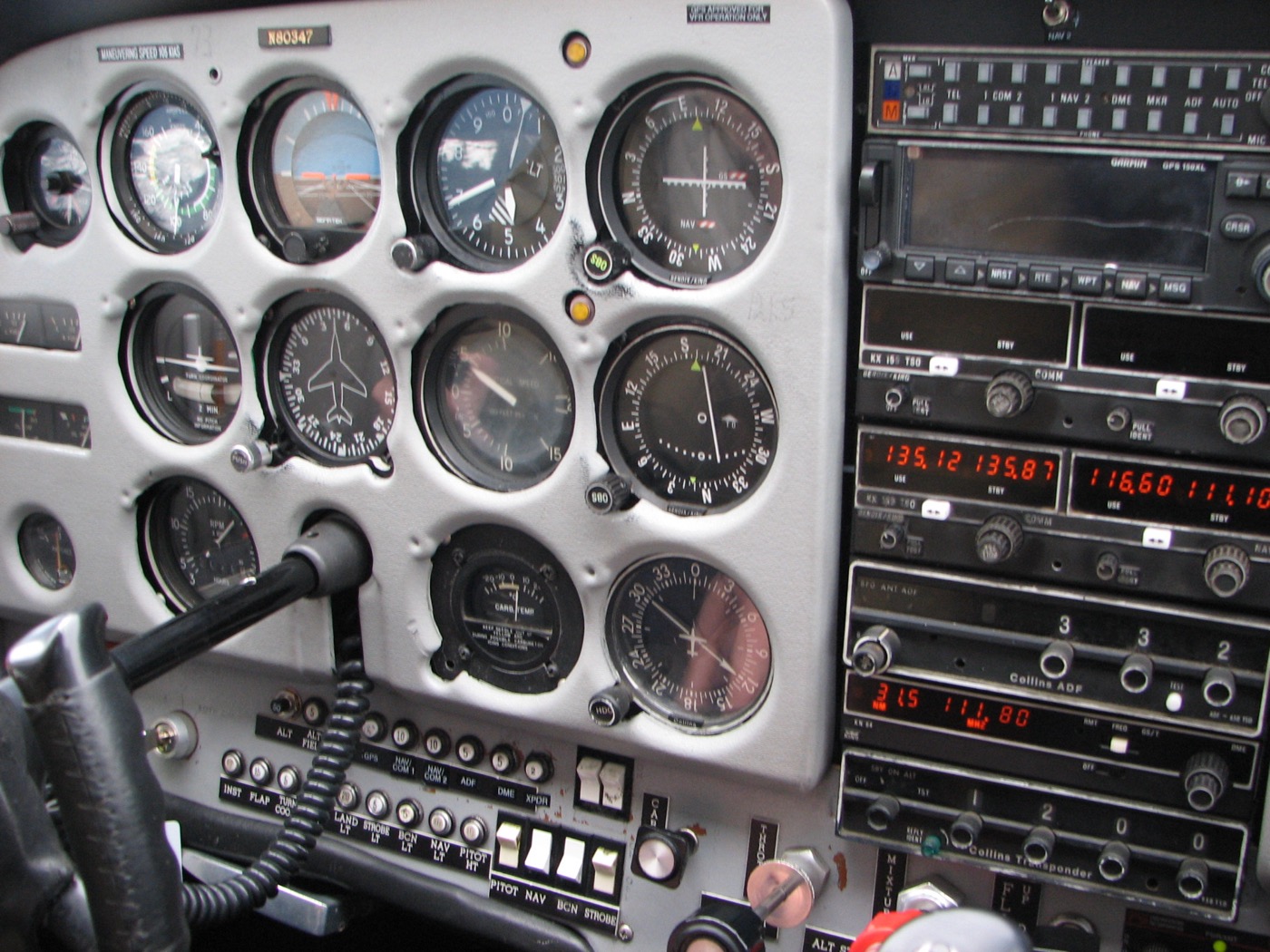 A Cessna 172 instrument panel showing the standard six-pack: top row airspeed indicator, attitude indicator, altimeter; bottom row turn coordinator, heading indicator, vertical speed indicator, with the magnetic compass mounted on the windshield post above